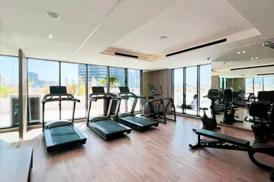a gym with treadmills and ellipticals in a room with windows at Fully Furnished Luxe 1BR In JVC in Dubai
