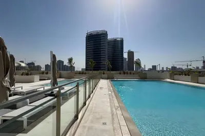 a swimming pool with a city skyline in the background at Fully Furnished Luxe 1BR In JVC in Dubai