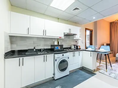 a kitchen with white cabinets and a washer at Elite Vista Studio Elite 10 Sports Residences in Dubai