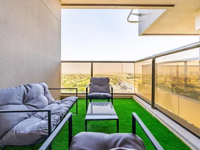 a balcony with two chairs and green grass at Elite Vista Studio Elite 10 Sports Residences in Dubai