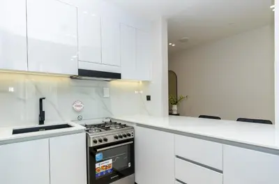 a kitchen with white cabinets and a stove top oven at CitiHome - 1BR Freshly Styled and Comfortable in JVC in Dubai