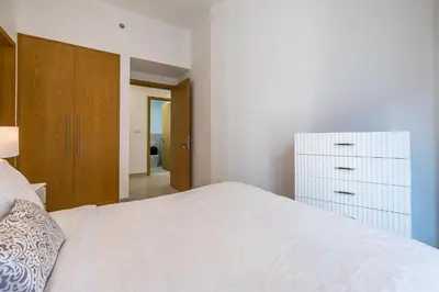 a bedroom with a white bed and a dresser at Apartment with Burj Khalifa View I Bellevue Tower in Dubai