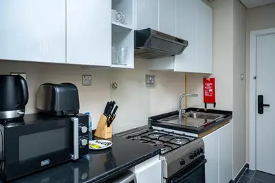 a kitchen with a stove and a microwave at Escape24 Studio at Loreto with Community View in Dubai