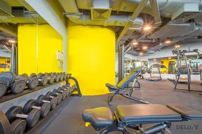 a gym with tread machines and yellow walls at Jubilant Studio at Sky Gardens, DIFC by Deluxe Holiday Homes in Dubai
