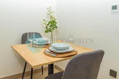 a dining room table with chairs and a vase on it at Bloomfields Cozy Stu Azizi Riviera Meydan in Dubai