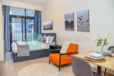 a living room with a dining table and a bedroom at Bloomfields Cozy Stu Azizi Riviera Meydan in Dubai