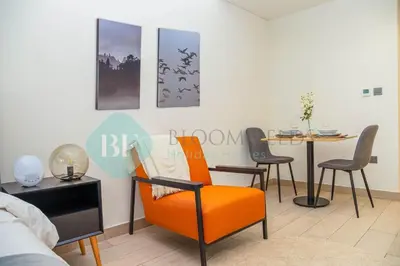 a living room with an orange chair and a table at Bloomfields Cozy Stu Azizi Riviera Meydan in Dubai