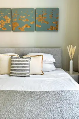 a bedroom with a bed with four paintings on the wall at GuestReady - Luxury haven at Marina Arcade in Dubai