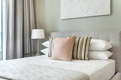 a bedroom with a bed with a pink pillow on it at GuestReady - Luxury haven at Marina Arcade in Dubai