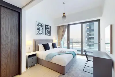 a bedroom with a bed and a desk and a window at Silverene Tower B - Bright Two Bedroom in Dubai