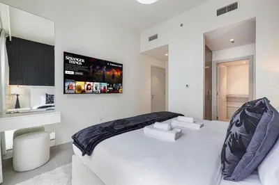 a white bedroom with a large bed and a tv at Luxury 4BR Burj Khalifa & Fountain Views in Dubai