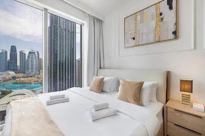 a bedroom with a large white bed with a large window at Luxury 4BR Burj Khalifa & Fountain Views in Dubai