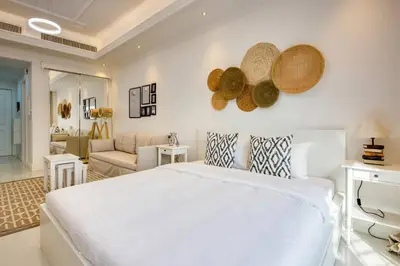 a bedroom with a white bed and a living room at Studio Apartment in Vincitore Palacio Arjan in Dubai