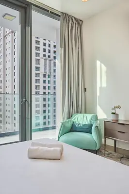 a bedroom with a blue chair and a large window at Luxury Living in Marina Liv Residence 2BR in Dubai