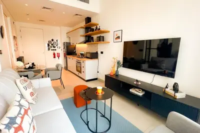 a living room with a white couch and a large television at Brand New Apartment in Socio Tower Dubai Hills in Dubai