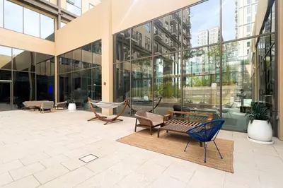 a large glass building with a bench and chairs at Brand New Apartment in Socio Tower Dubai Hills in Dubai