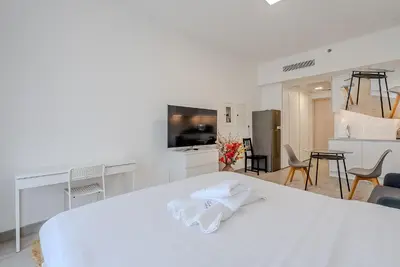 a white room with a white bed and a kitchen at Modern and Cozy Studio in JVC I Luma Building in Dubai