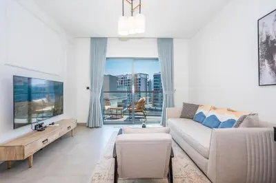 a living room with a couch and a tv at Vacay Lettings - Waves Grande - Sobha Hartland in Dubai
