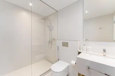 a white bathroom with a toilet and a shower at Beachfront Luxury Living at La Vie Residence JBR in Dubai