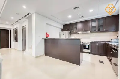a large kitchen with brown cabinets and a counter top at Keysplease Beautiful 3 B/R Villa With Garden, Serena in Dubai