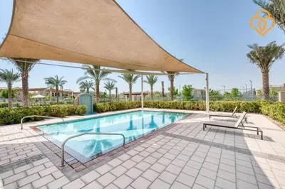 a swimming pool in a resort with a large umbrella at Keysplease Beautiful 3 B/R Villa With Garden, Serena in Dubai