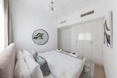 a white bedroom with a bed and a couch at Comfortable 2BD apartment next to metro & mall in Dubai