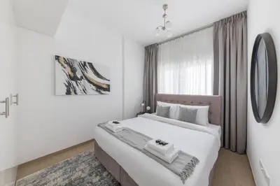 a white bedroom with a large bed and a window at Comfortable 2BD apartment next to metro & mall in Dubai