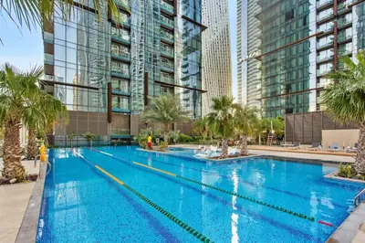 a large swimming pool with palm trees and buildings at Marina Gate - Stunning 56 Floor Full Sea Views in Dubai