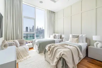 two beds in a white room with a window at Oceana Luxury 4 BR Apartment with Resort Access and Sea Views by Exclusive Holiday Homes in Dubai