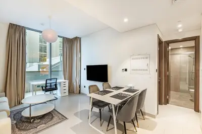 a living room with a table and chairs and a television at Sobha Creek Vistas Cozy 1BDR with balcony in Dubai