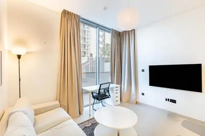 a living room with a white couch and a tv at Sobha Creek Vistas Cozy 1BDR with balcony in Dubai