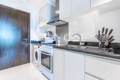 a kitchen with white cabinets and a washer and dryer at Staycae Holiday Homes - Carson Towers in Dubai