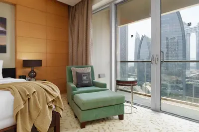 a bedroom with a bed and a chair and a window at Maison Privee - Fabulous Studio with Direct Burj Khalifa Views in Dubai