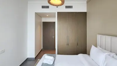 a bedroom with a white bed and a closet at Chic New 2BR Dubai Creek Gate by Tanami Holiday Homes in Dubai