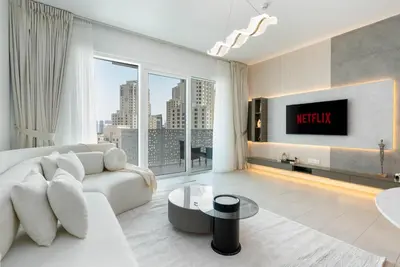 a living room with a white couch and a large window at Ahlan HH - Luxurious 1BR Suite at La Vie - Free Private Beach Access in Dubai