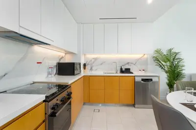 a kitchen with white walls and yellow cabinets at Ahlan HH - Luxurious 1BR Suite at La Vie - Free Private Beach Access in Dubai