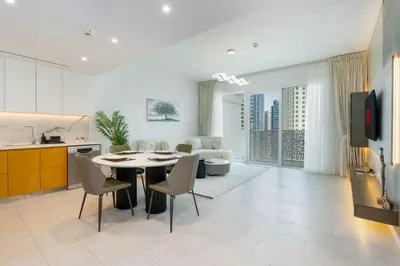a kitchen and living room with a table and chairs at Ahlan HH - Luxurious 1BR Suite at La Vie - Free Private Beach Access in Dubai