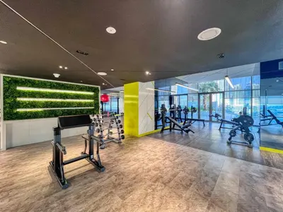 a gym with treadmills and a green wall at GuestReady - Contemporary studio in Business Bay in Dubai