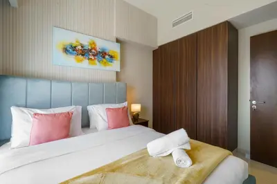 a bedroom with a bed with pink and white pillows at 1BR near Dubai Mall 10 Min walking distance in Dubai