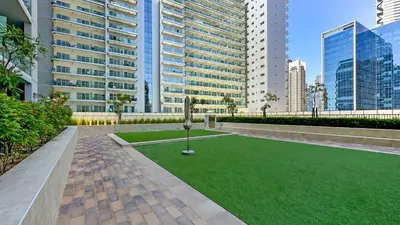 a green lawn in a city with tall buildings at 1BR near Dubai Mall 10 Min walking distance in Dubai
