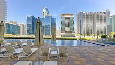 a group of chairs and umbrellas in front of a city at 1BR near Dubai Mall 10 Min walking distance in Dubai