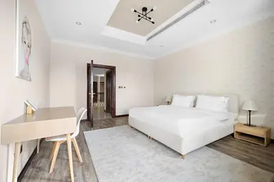a white bedroom with a white bed and a desk at Beachfront Dubai Villa for 10 Guests with Full Kitchen & View in Dubai