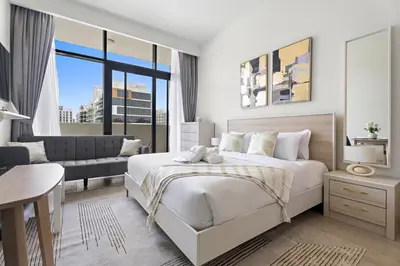 a white bedroom with a bed and a desk at StoneTree - Azizi Riviera 36 Studio - Brand new in Dubai
