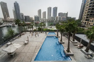 a view of a pool with palm trees and a city at izzzi - One Bedroom Apartment, Sparkle Tower in Dubai