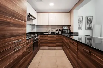 a large kitchen with wooden cabinets and appliances at izzzi - One Bedroom Apartment, Sparkle Tower in Dubai