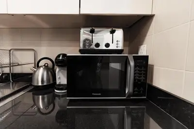 a microwave oven sitting on top of a kitchen counter at izzzi - One Bedroom Apartment, Sparkle Tower in Dubai