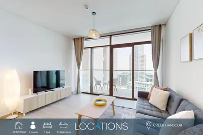 a living room with a couch and a tv at Palace Residences - Modern One Bedroom in Dubai