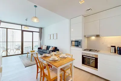 a kitchen and living room with a table and chairs at Palace Residences - Modern One Bedroom in Dubai