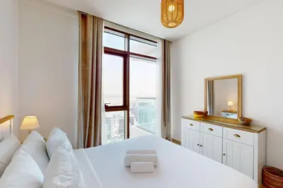 a bedroom with a white bed with a mirror and a window at Palace Residences - Modern One Bedroom in Dubai