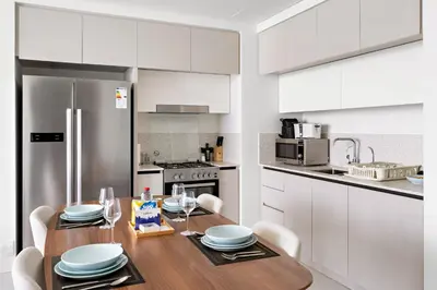 a kitchen with a wooden table and white cabinets at Silkhaus Skyline View | Exclusive Neighbourhood in Dubai